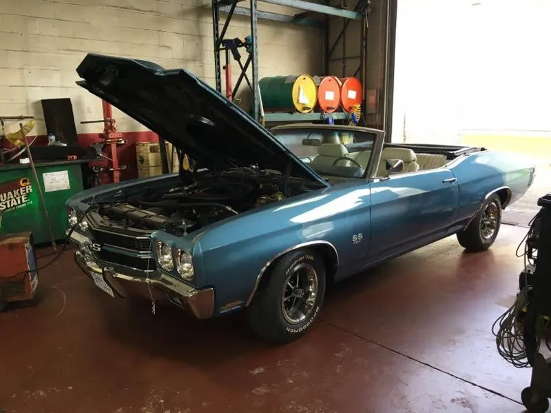 A classic blue Chevelle with the hood up in the shop